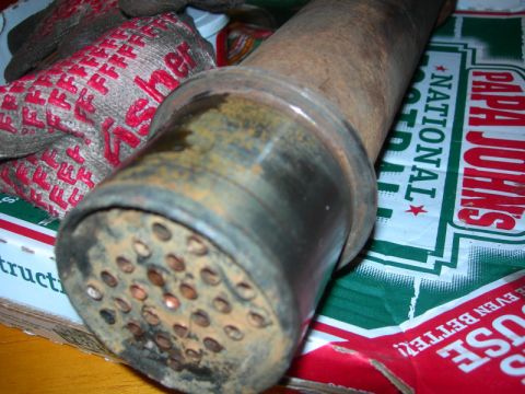 1984 Ford Bronco - A rusty exhaust pipe with a perforated end is shown, placed on a Papa John's pizza box, with work gloves in the background.