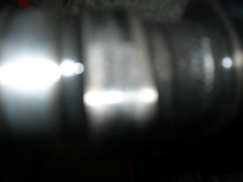 blurry close-up of a metallic engine component with bright light reflections