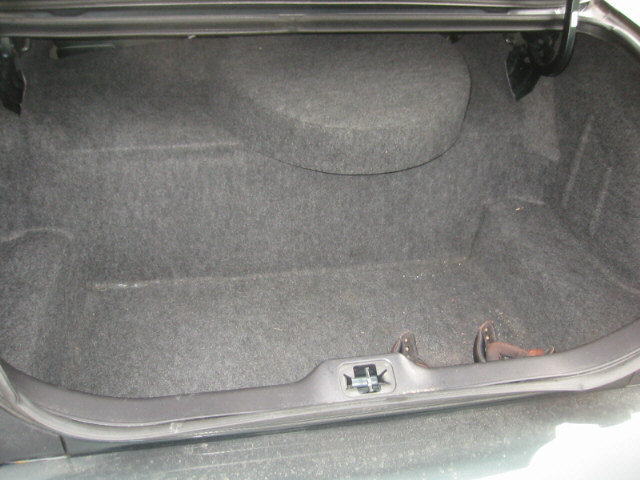 Empty carpeted sedan trunk interior with lid open