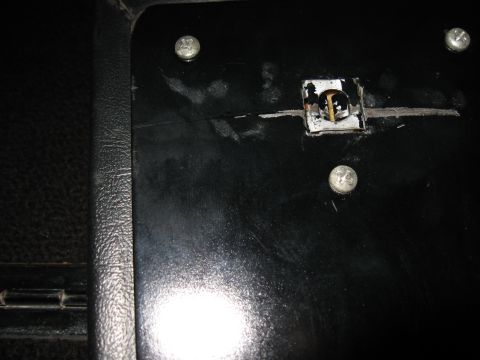 1968 Shelby GT500 - Close-up view of a vehicle's interior panel, showing a damaged latch mechanism and mounting screws.