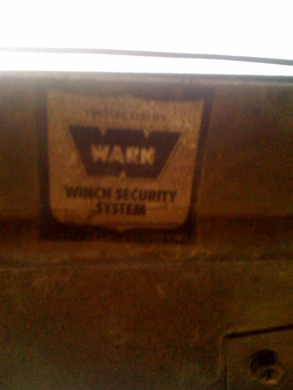 WARN winch security system sticker on a dark, textured surface