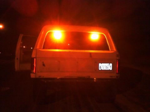 1986 Ford Bronco - Rear view of a 1986 Ford Bronco with its hazard lights illuminated at night.