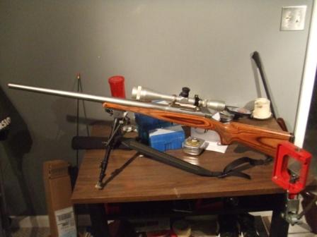 1996 Ford Bronco - A rifle with a wooden stock, scope, and bipod rests on a table next to ammunition boxes.