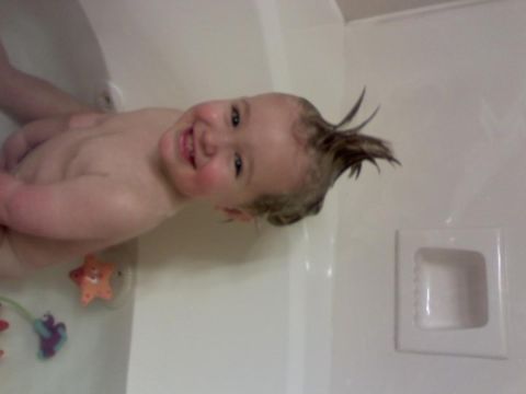 1994 Ford Bronco - A baby smiles widely while sitting in a bathtub, with toys visible in the water.
