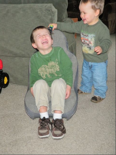 1994 Ford Bronco - A boy sits on a chair while his younger brother playfully teases him with a toy car.
