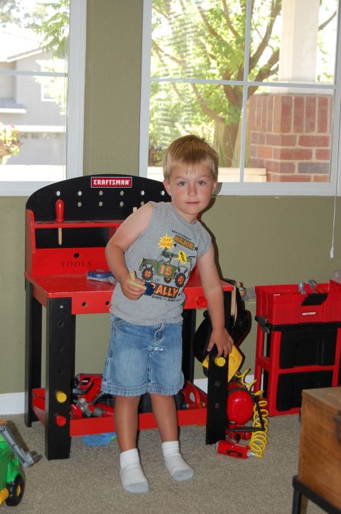1994 Ford Bronco - A young boy stands in front of a toy workbench, holding a toy tool.