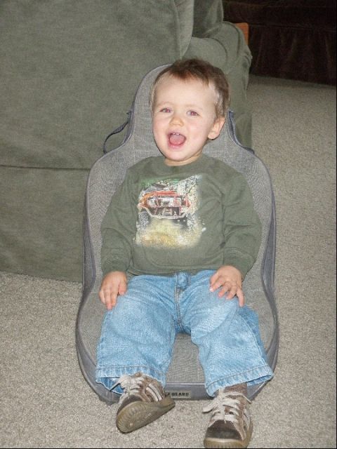 1994 Ford Bronco - A young child is seated in a car seat, looking forward with an open mouth.