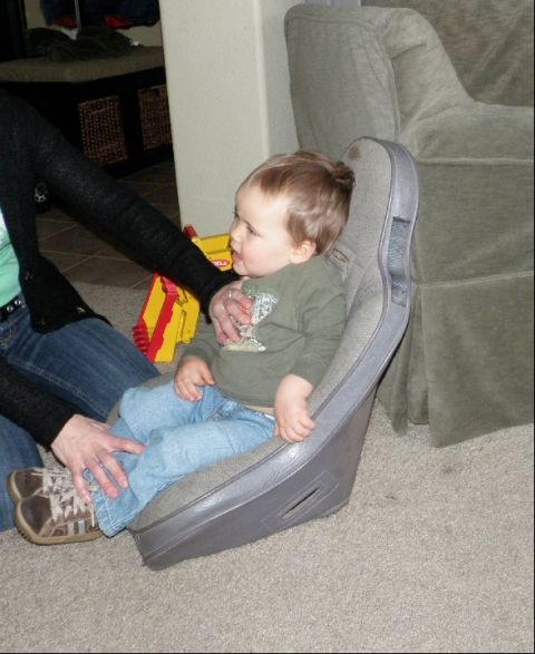 1994 Ford Bronco - A child sits in a car seat, with adult legs and shoes nearby on a carpeted floor.