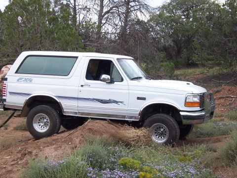 1996 Ford Bronco - This white 1996 Ford Bronco is shown in a side profile, navigating an off-road terrain with its FX4 Off-Road decal visible.