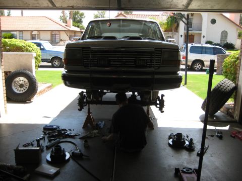 1996 Ford Bronco - A 1992 Ford Bronco is undergoing repairs in a garage, with its front end elevated and various tools laid out around it.