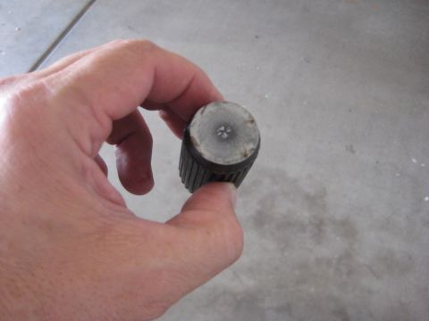 1996 Ford Bronco - A hand holds a small, cylindrical part with a ribbed exterior and a star-like imprint on its end.