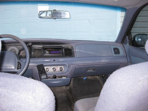 1999 Ford Crown Victoria - Interior view of a car's dashboard and seats, showing the steering wheel and radio.
