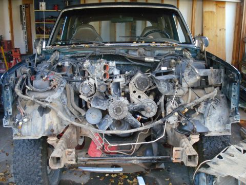 1993 Ford Bronco - The front end of a vehicle is removed, exposing the engine and surrounding mechanical parts for repair or maintenance.