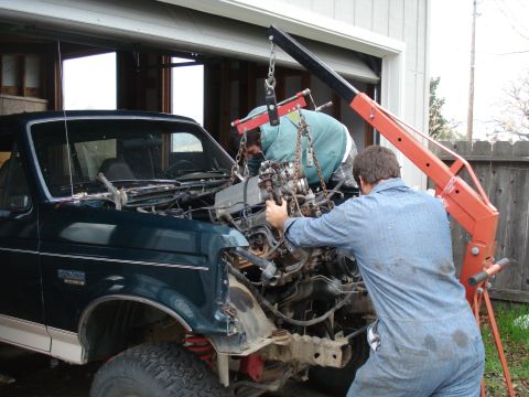 1993 Ford Bronco - Mechanics use an engine hoist to remove the engine from a 1993 Ford Bronco during a rebuild.