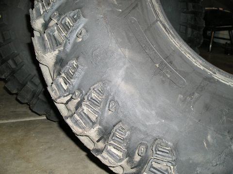 1986 Toyota Hilux - This off-road tire shows significant damage to its tread blocks, indicating heavy use or abuse.