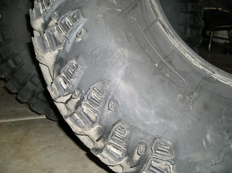 Close-up of a damaged off-road tire with torn tread blocks