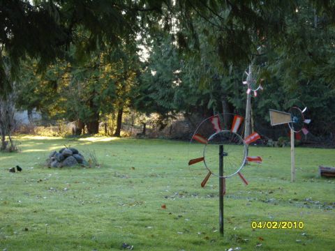 1989 Ford Bronco - A grassy yard is decorated with three homemade windmills under a canopy of trees.