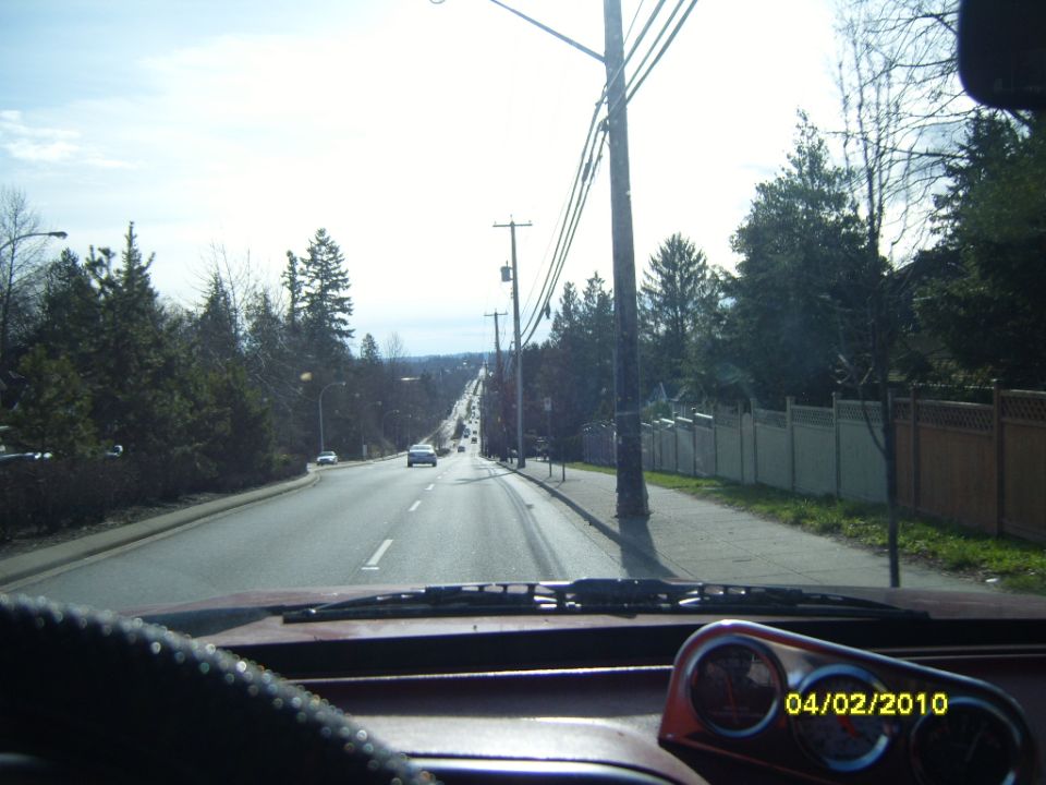 Dashboard view of a road with other cars and trees