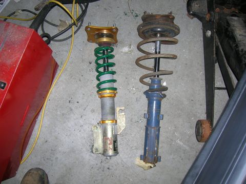 1987 Mazda RX-7 - Comparison of two shock absorbers, one a green spring and adjustable gold components, alongside a blue, weathered unit.