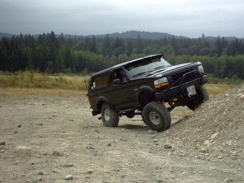 1995 Ford Bronco - Black 1995 Ford Bronco navigates a steep dirt hill with off-road tires and a modified bumper.
