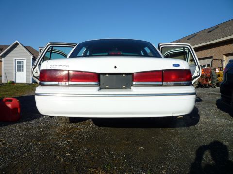 1997 Ford Crown Victoria - Rear view of a white 1997 Ford Crown Victoria, doors open, parked outdoors.