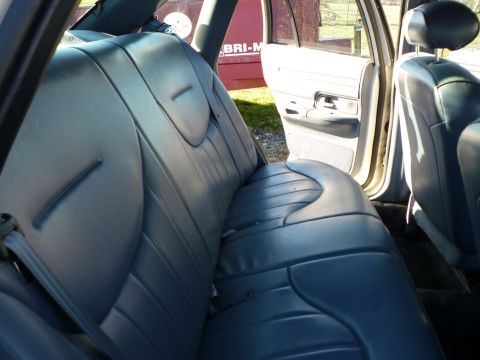 1997 Ford Crown Victoria - The interior of a vehicle is shown, focusing on the rear seats and the open passenger door.