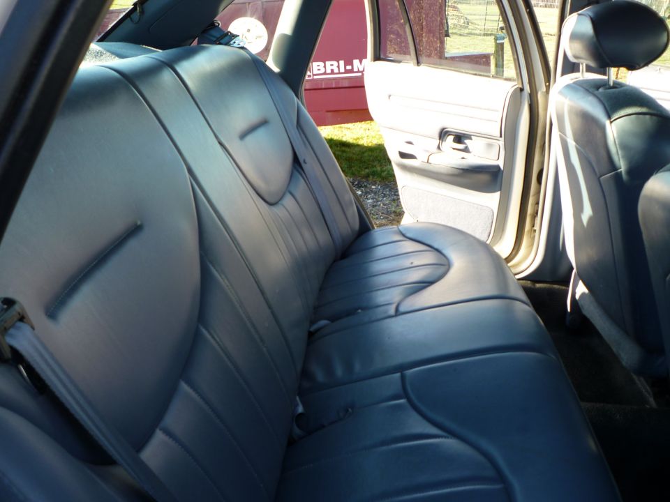 Interior rear seats of a car, showing blue upholstery and an open door