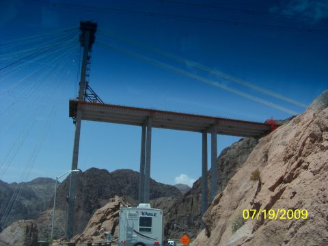 2009 Kenworth T800 - A bridge is under construction with support pillars and cables visible against a clear blue sky.