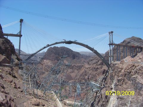 2009 Kenworth T800 - Construction of a large bridge over a canyon, with steel framework and suspension cables visible.
