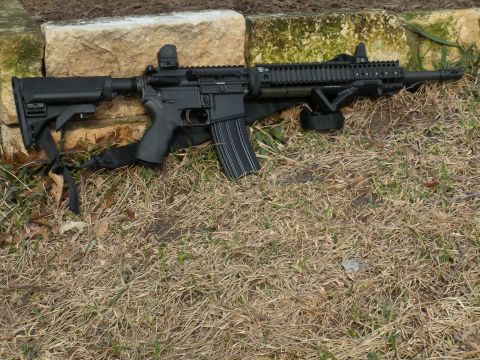 1996 Ford Bronco - An AR-15 style rifle with a loaded magazine is placed on the ground next to some rocks.