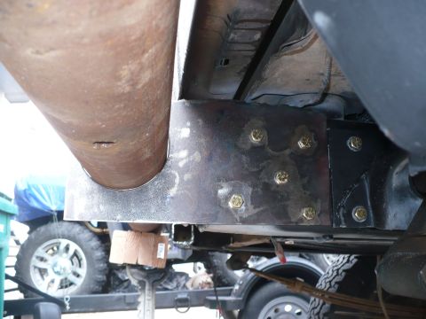 1979 Ford Bronco - Undercarriage view shows a modified frame with a large pipe and bolted bracket, with other vehicles visible in the background.