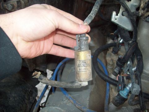 1985 Ford Bronco - A hand holds a gold Ford part with visible part numbers and labels.