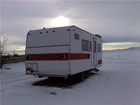 1985 Ford Bronco - This travel trailer is parked in a snowy field under a cloudy sky.