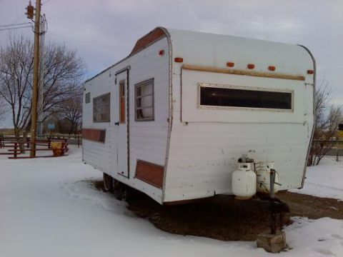1985 Ford Bronco - A white travel trailer sits in a snowy landscape, with two propane tanks visible at the front.