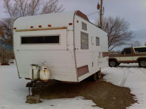 1985 Ford Bronco - A two-tone Ford Bronco is seen in a snowy environment beside a travel trailer.