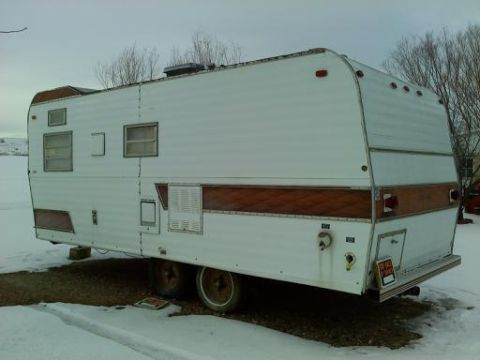 1985 Ford Bronco - This travel trailer is seen parked outdoors in a snowy environment, white siding and brown decorative trim.