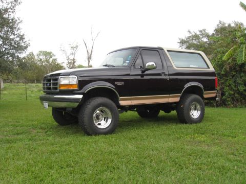 1994 Ford Bronco - This lifted Ford Bronco sits on a grassy lawn under an overcast sky.