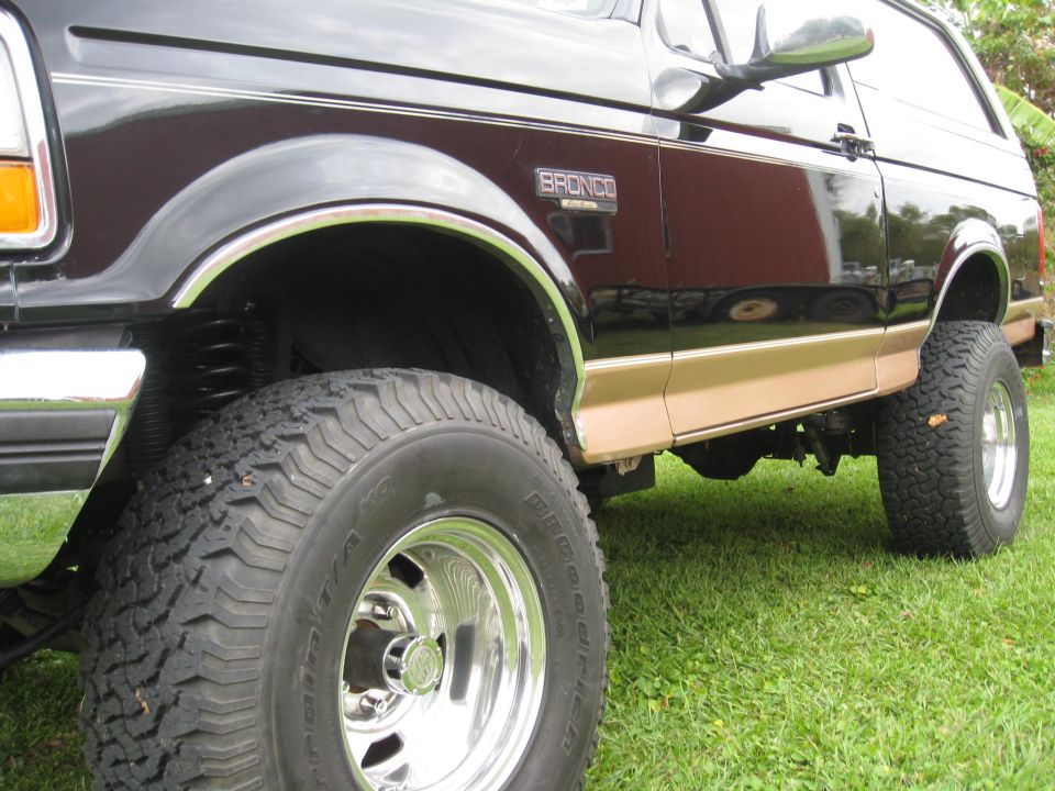 Front fender and mud tire of lifted two-tone black-and-tan full-size Bronco