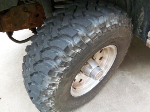 1987 Ford Bronco - A close-up view of a off-road tire and wheel assembly, with visible suspension components.
