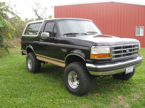 1994 Ford Bronco - This black 1994 Ford Bronco features a tan accent stripe and a lifted suspension with large tires.