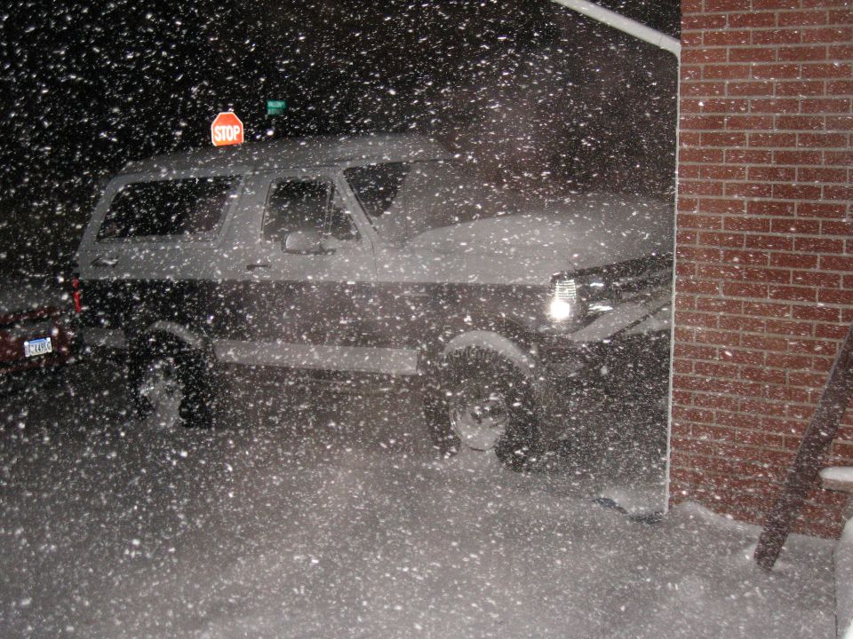 1992 Ford Bronco parked next to a brick wall during a snowstorm