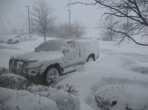 2000 Ford Crown Victoria - An SUV is heavily covered in snow during a blizzard, with another vehicle visible in the background.