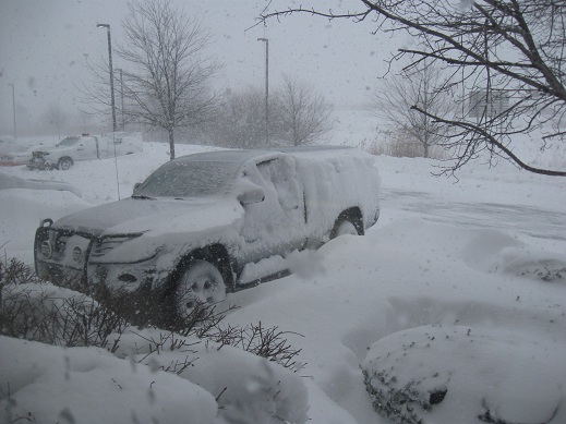 SUV buried in snow with a bull bar, parked next to another snow-covered vehicle