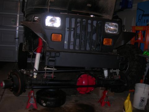 1991 Jeep Wrangler - The front axle and suspension of a Jeep Wrangler are being worked on in a garage.