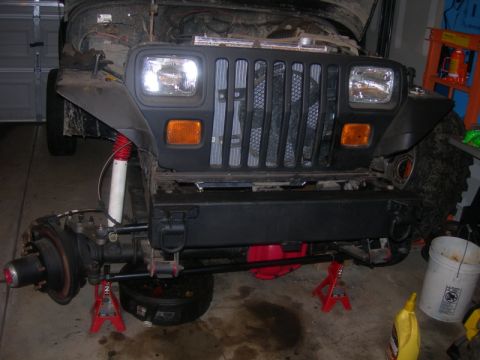 1991 Jeep Wrangler - Front axle and suspension of a 1991 Jeep Wrangler undergoing work in a garage.