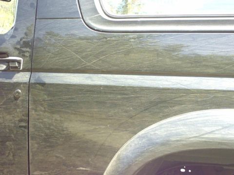 1995 Ford Bronco - Side view of a heavily scratched 1995 Ford Bronco door and fender.