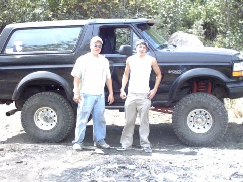 1995 Ford Bronco - A lifted 1995 Ford Bronco is shown with two people posing next to it.