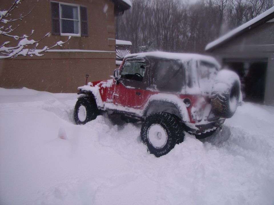 Red 2003 Jeep Wrangler stuck in deep snow, side view