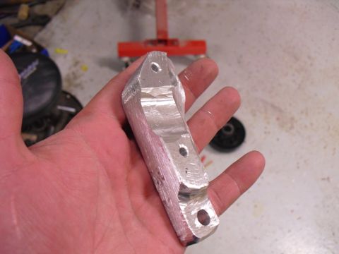 1996 Ford Bronco - Machined aluminum bracket with three bolt holes is held in a hand.
