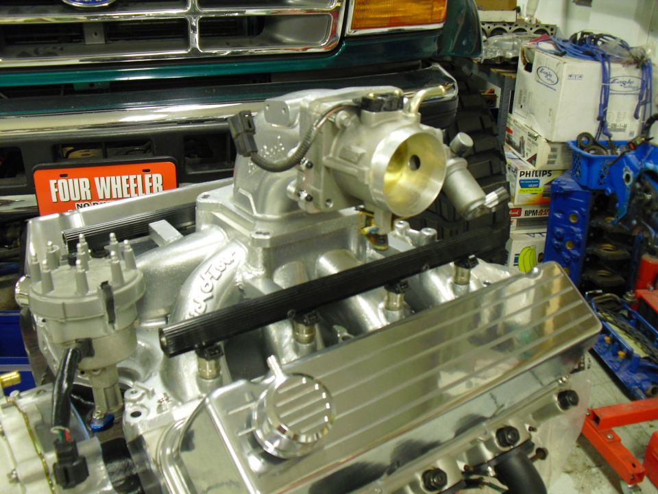 Rebuilt V8 engine with polished intake and chrome valve cover in a garage